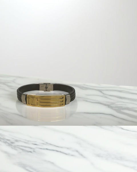 Pulsera negra con rayas y detalles dorados